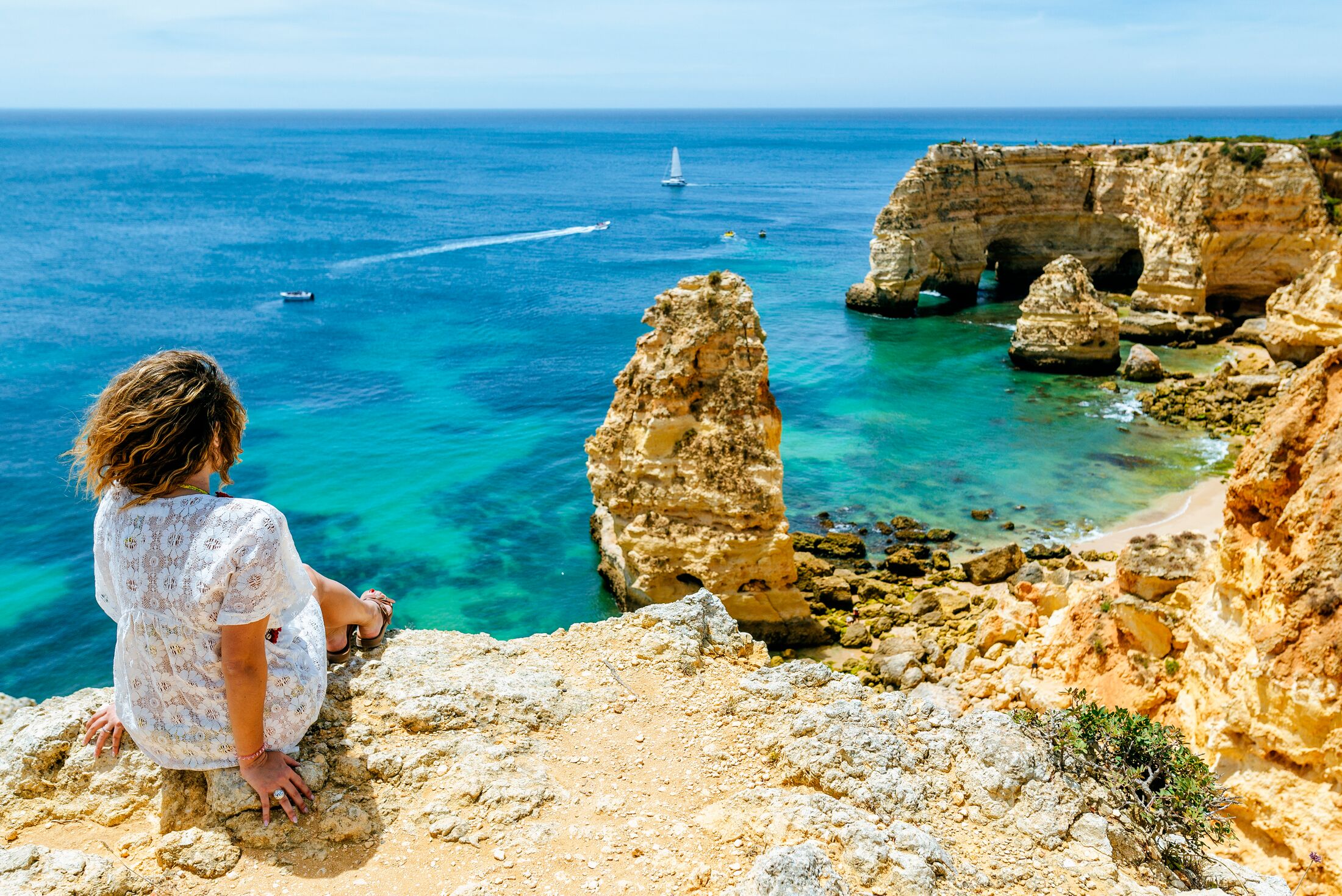 Woman on the cliffs looking towards at Marina beach, el Algarve, Portugal