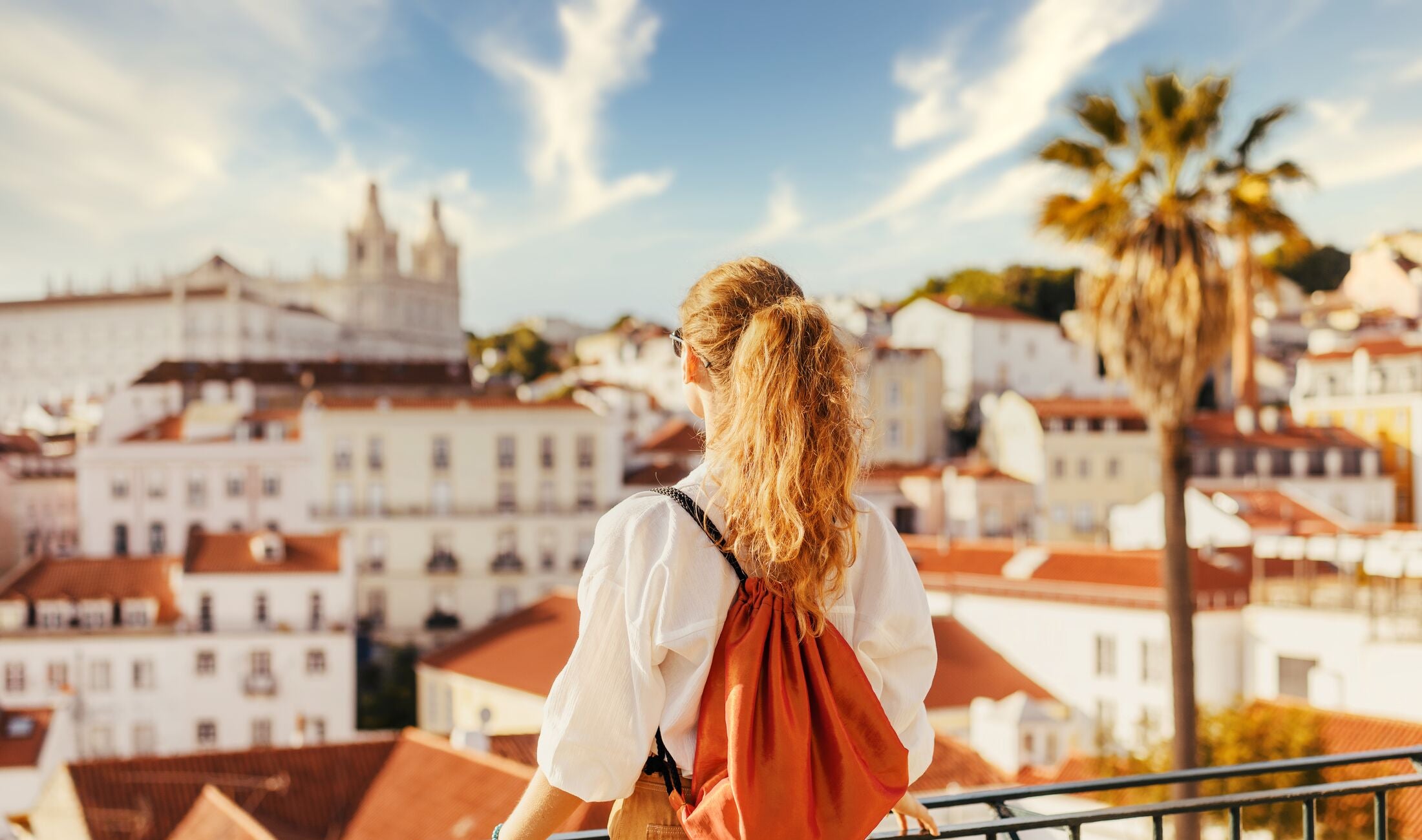 Young tourist traveling through beautiful sunny european city and looking at view, rear view