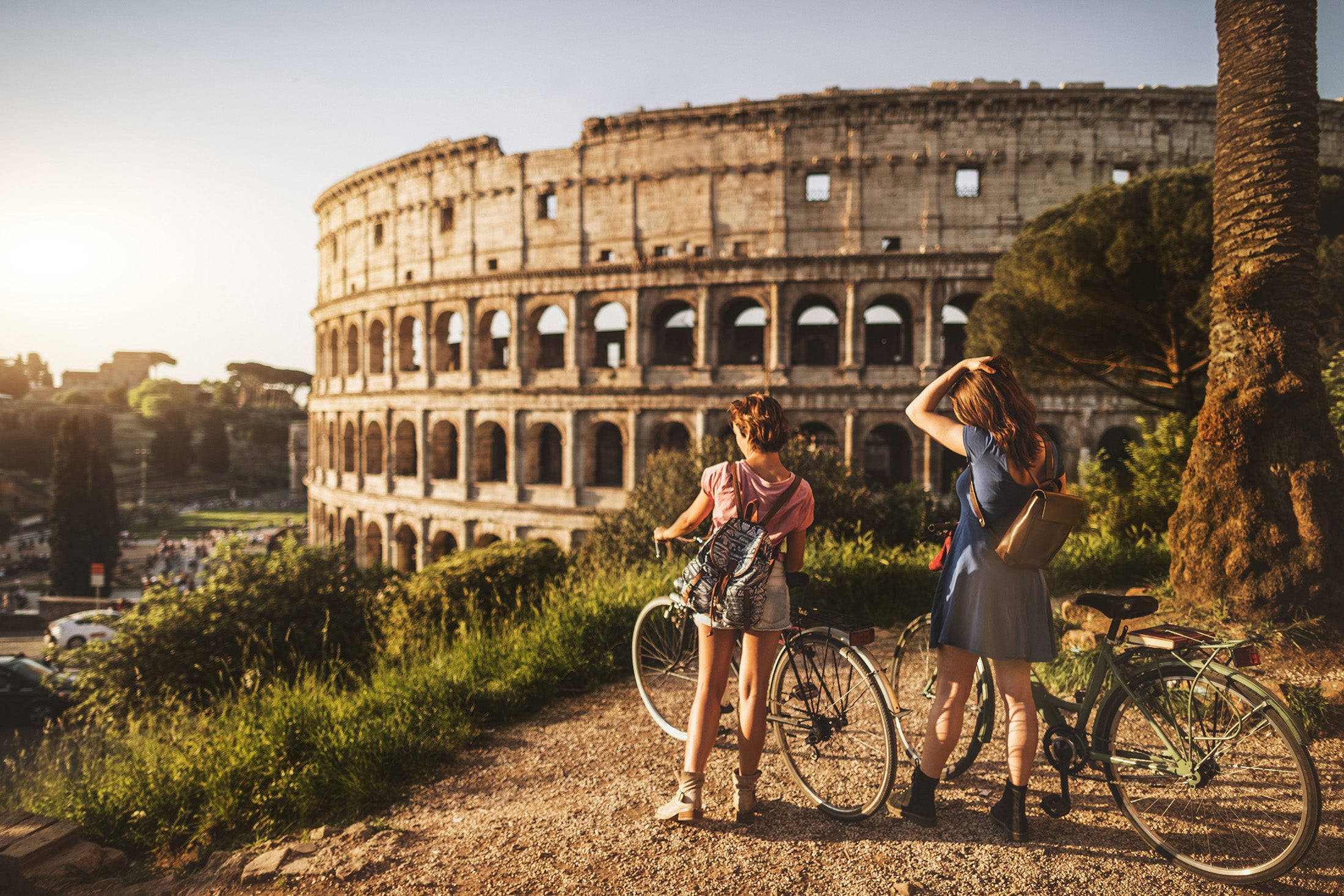 Deux femmes à vélo devant le Colisée à Rome.